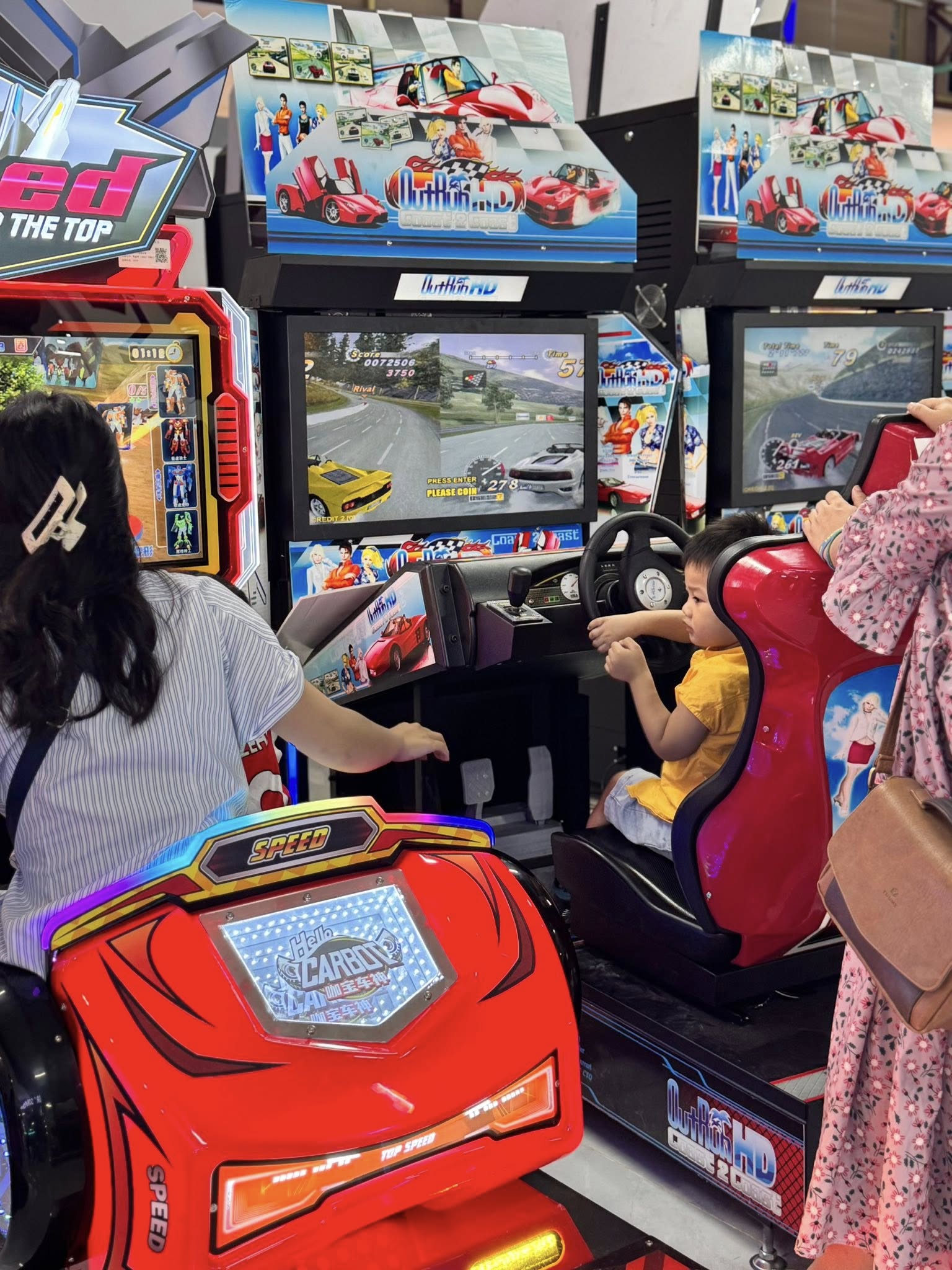 khách hàng đang chơi máy game đua xe Speed ngồi trong cabin xe đua đỏ với đèn LED xanh tím màn hình hiển thị xe đua trên đường phố khách hàng đang chơi máy game đua xe Speed ngồi trong cabin xe đua đỏ với đèn LED xanh tím màn hình hiển thị xe đua trên đường phố