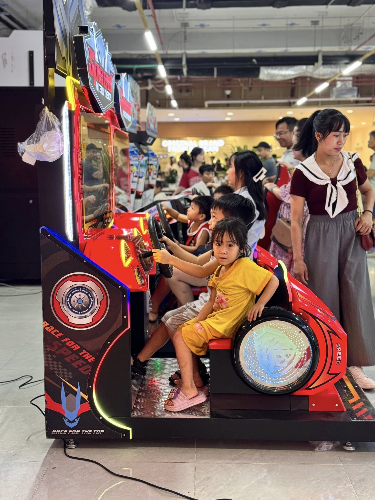 Khu vực máy game đua xe arcade trong trung tâm thương mại nhiều cabin rực rỡ Khu vực máy game đua xe arcade trong trung tâm thương mại nhiều cabin rực rỡ
